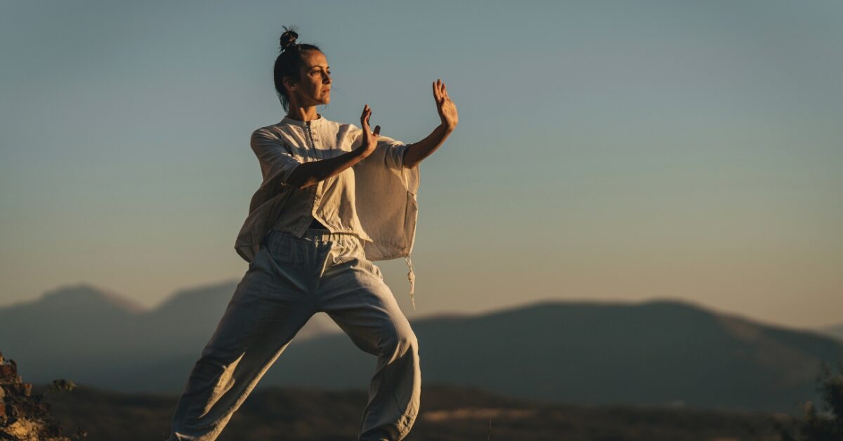 Pessoa praticando Tai Chi ao ar livre, ilustrando práticas da medicina chinesa para equilíbrio energético e bem-estar integral.